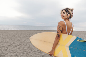 Portrait of a surfer woman posing with surfboard on a beach