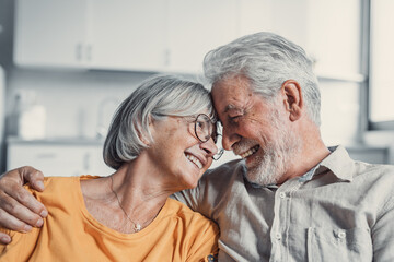 Happy mature husband and wife sit rest on couch at home hugging and cuddling, show care affection, smiling senior loving couple relax on sofa have fun, enjoy tender romantic family weekend together.