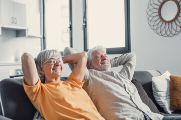 Peaceful middle aged man and woman with closed eyes relaxing on comfortable couch at home, mature...