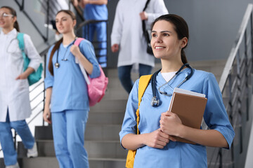 Portrait of medical student with books on staircase in college, space for text