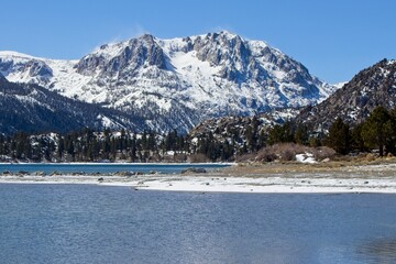 Snow tops the Sierra Nevada Mountains from the crystal clear waters of June Lake, which sits at the...