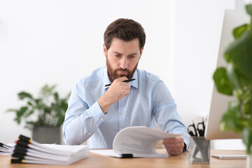 Naklejka premium Businessman working with documents at wooden table in office
