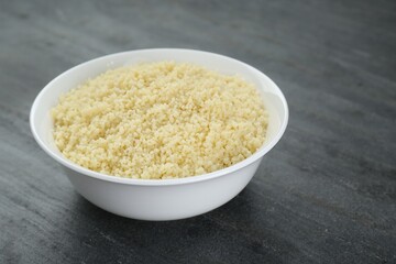 Bowl of tasty couscous on grey table, closeup