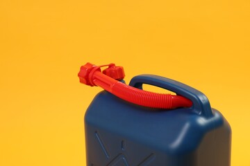 Blue plastic canister with tube on orange background, closeup. Space for text