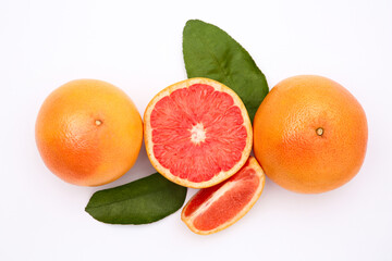Fresh grapefruits and green leaves on white background, flat lay