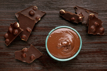 Bowl with tasty paste and pieces of chocolate on wooden table, flat lay
