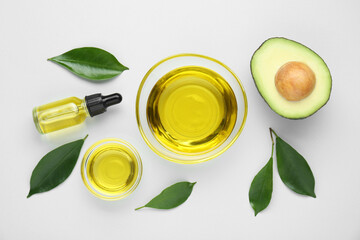 Essential oil, fresh cut avocado and leaves on white background, flat lay