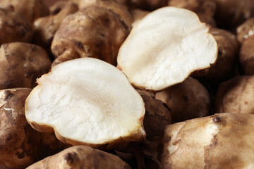 Whole and cut Jerusalem artichokes as background, closeup