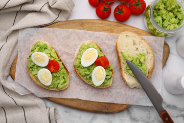 Delicious sandwiches with guacamole, eggs and tomatoes on white table, flat lay
