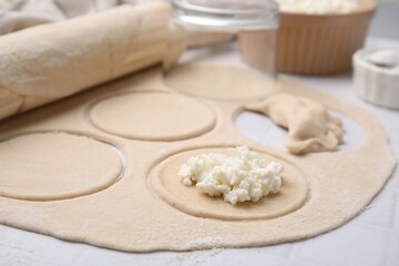 Process of making dumplings (varenyky) with cottage cheese. Raw dough and ingredients on white table, closeup