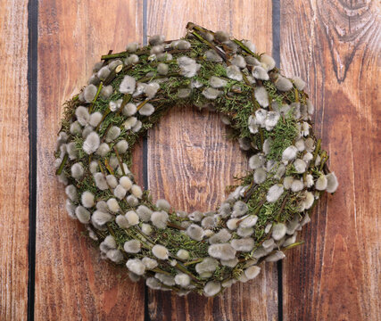 Wreath made of beautiful willow flowers on wooden table, top view
