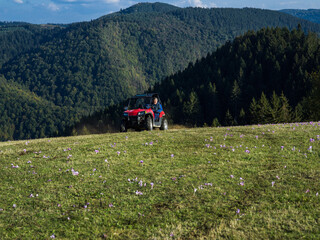 Fototapeta na wymiar A man driving a quad ATV motorcycle through beautiful meadow landscapes