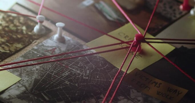 Camera pans around a pin and strings  on investigation board that lead to solving a criminal case
