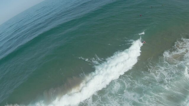 Bodyboarder takes off and rides along crashing white wave and performs tricks