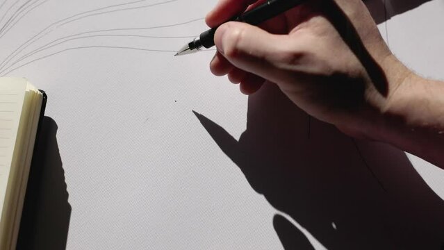 The young artist takes a pen with black ink and draws abstract lines on the canvas. Designer at work. Abstract art