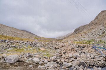 The rock is located below the mountain and clouds sky at Ladakh, India