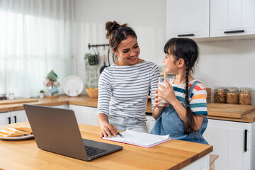 Caucasian young girl kid learning online class at home with mother. 