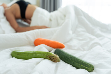 Close up of cucumber foods for erotic sex education on bed in bedroom.  - obrazy, fototapety, plakaty