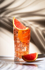 Grand Sazerac alcohol cocktail drink with whiskey, liqueur, bitter, absinthe, prosecco, garnished with orange zest in highball glass. Beige background, hard light, shadow pattern