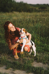 Beautiful woman plays with her Jack Russell dog in the park. The concept of animals, friendship, people and love. a woman lies on the grass and plays with a jack russell terrier