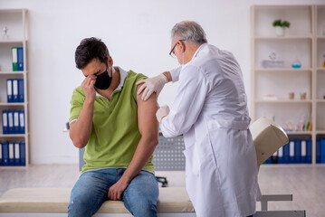 Obraz premium Young male patient visiting old male doctor in vaccination conce