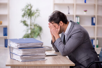Naklejka premium Young male employee and too much work in the office