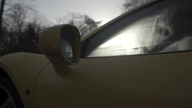 Morning sun shining through the window full of dew of a yellow sportscar LOG
