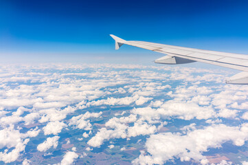 Fototapeta premium View from the airplane window at a beautiful cloudy sky and the airplane wing