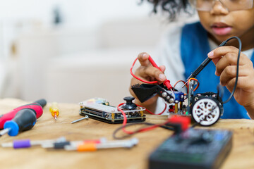 Happy cheerful American - African ethnicity girl enjoy learning to assemble a robot by herself.