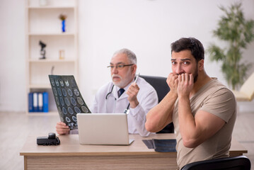 Obraz premium Young male patient visiting old male doctor radiologist