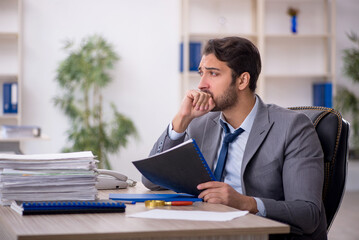 Young male employee and too much work in the office