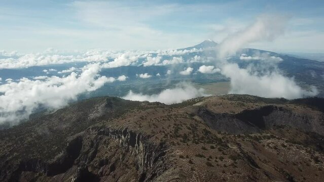 Flight from the summit of Cofre de Perote National Park towards Pico de Orizaba, Citlaltepetl, with fog rising from the forest.