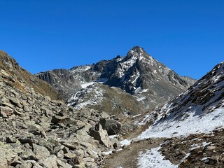 Obraz premium Hiking trails or mountaineering routes in the autumn Swiss Alpine environment of the Albula Alps and above the mountain road pass Fluela (Flüelapass), Zernez - Canton of Grisons, Switzerland (Schweiz)