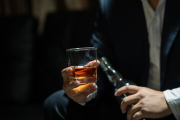 Businessman sitting and holding glass of whiskey
