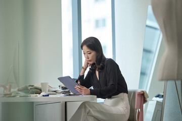 턱을 괴고 태블릿을 보며 사무실에 앉아있는 여성 리더