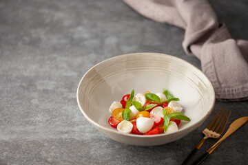 Salad with basil leaves, mozzarella and tomatoes in a plate on the table. Caprese salad.