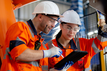 Engineer man and woman talking and discussion about robot arms technology intelligence and innovation while looking digital tablet at factory, people meeting and check machine robot, industry concept.
