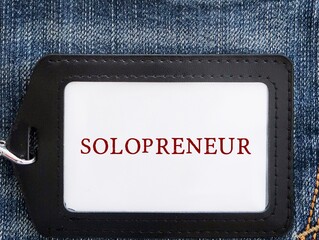 Black ID card holder on jeans background with text written SOLOPRENEUR, person who sets up and runs...