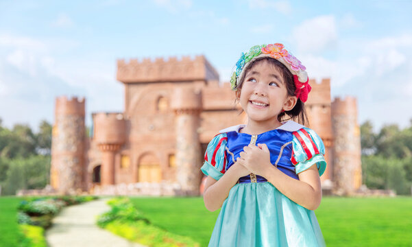 asian girls with princess dress with fairy tale castle on background. Asian kids with princess costume happy action as dreaming on classic castle background