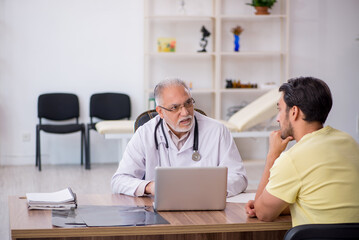 Obraz premium Young male patient visiting old male doctor