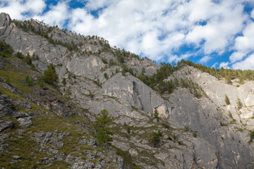 A large mountain with a sheer cliff close-up against the sky. Hiking tourism. Mountains of the Altai Mountains, Altai Republic