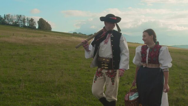 Traditional Slovak couple walking on field to work.