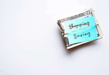 on white copy space, cash dollars money with note written SHOPPING (cross to) SAVING - concept of personal finance goal setting to start saving instead of spending money, for financial security