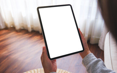 Mockup image of a woman holding digital tablet with blank desktop screen while lying on a sofa at home