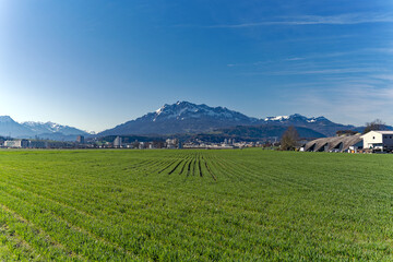 Fototapeta na wymiar Scenic landscape and Swiss Alps with agriculture field and mount Pilatus seen from City of Emmen, Canton Lucerne, on a sunny spring day. Photo taken March 22nd, 2023, Emmen, Switzerland.