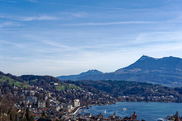 Fototapeta premium Aerial view of famous Swiss City of Luzern with Reuss River, Chapel Bridge, Lake Lucerne and Swiss Alps on a sunny spring day. Photo taken March 22nd, 2023, Lucerne, Switzerland.