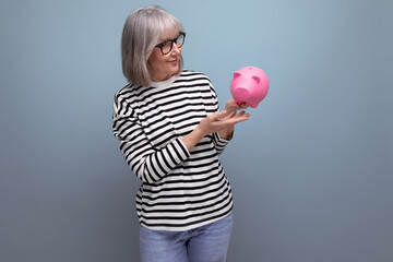 cute grandmother old woman 50s holding a piggy bank with a pension on a bright background with copy space