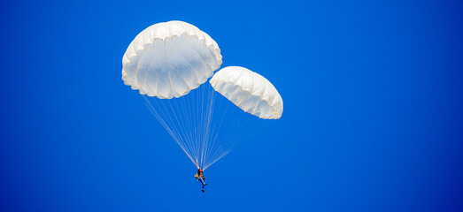 Skydiving. Flying parachutists against the background of the blue sky and mountains. Extreme sport and entertainment.