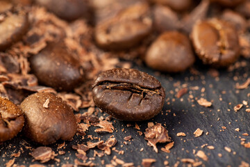 Roasted coffee beans lie together with chocolate crumbled into small pieces