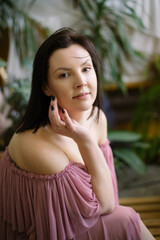 Close-up portrait of beautiful young woman indoors against background of green plants. Natural cosmetics. Hobby. 